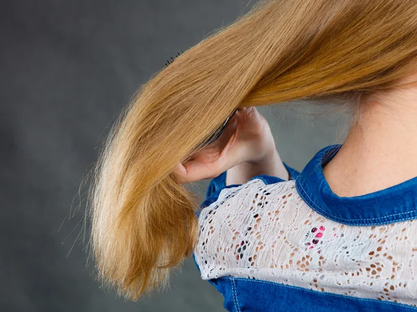 Blonde woman combing her hair.