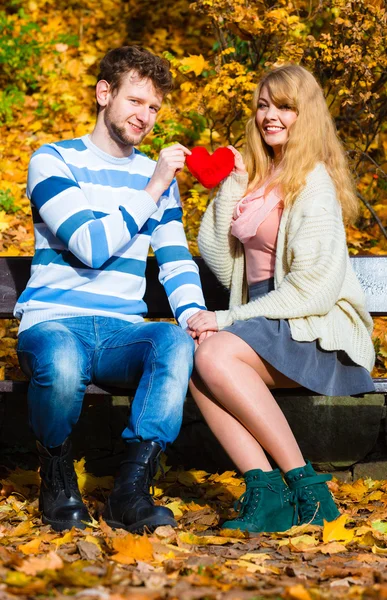 Romantic pair sit on bench in autumnal park — Stock Photo, Image