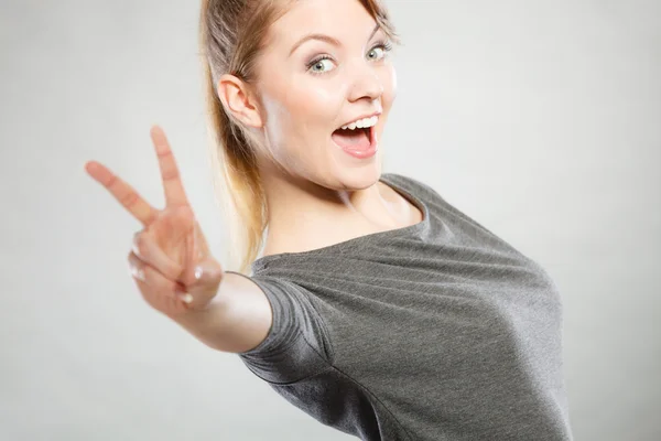 Fröhliche Frau zeigt Siegessymbol. — Stockfoto