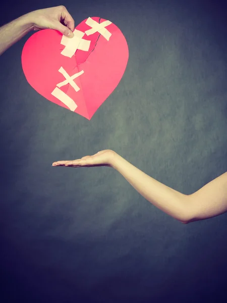 Woman and man hands holds broken heart. — Stock Photo, Image