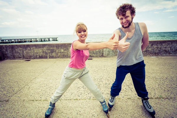 Two people exercise at seaside ride rollerblades. — Stock Photo, Image