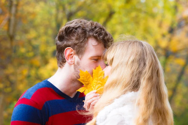 Couple avec feuille d'érable baisers dans le parc d'automne — Photo