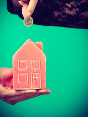 İnsanlar elleriyle küçük ev ve gümüş sikke.