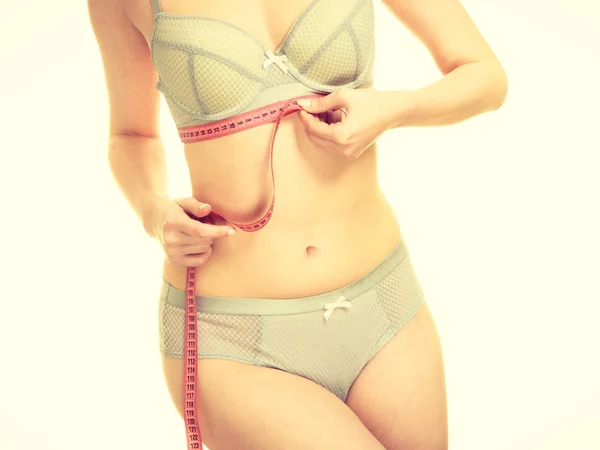 Mulher em lingerie sutiã medindo seus seios no peito . — Fotografia de Stock