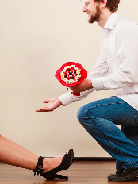 Uomo dando donna caramelle mazzo di fiori. Coppia felice — Foto Stock