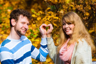 Sonbahar Park genç aşıklar kalp jest yapmak.