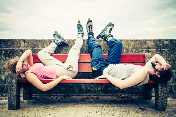 Young tired people friends relaxing on bench.