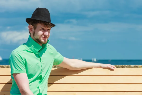 Young hipster man sitting on bench near the sea outdoor — Stock Photo, Image