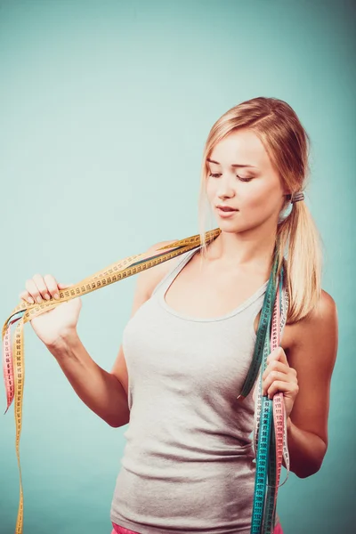 Fit girl with many colorful measure tapes on blue — Stock Photo, Image