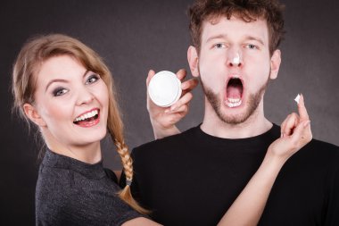 Kadın adamın yüzüne karşı krem uygulamak.