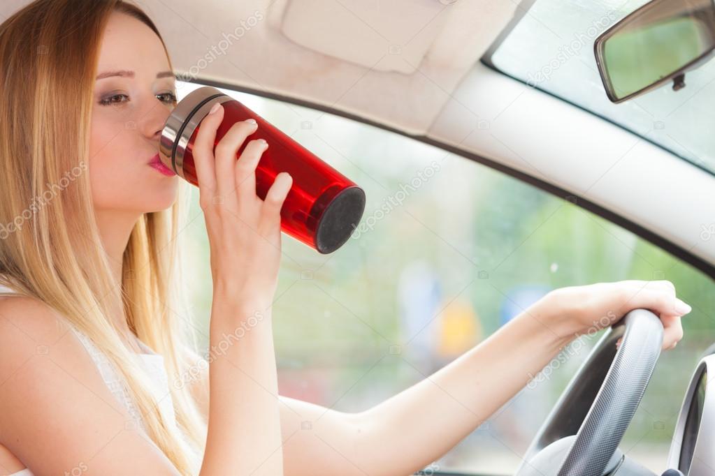 woman drinking coffee while driving her car