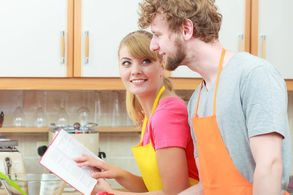 Couple cooking in kitchen reading cookbook — Stock Photo, Image