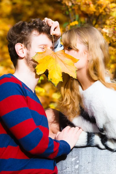 Casal com folha de bordo beijando no parque de outono — Fotografia de Stock