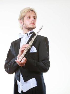 Klasik müzik eğitimi konsepti. Erkek flütçü müzisyen flüt çalıyor. Paltolu genç adam enstrüman tutuyor.