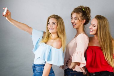 Moda kadınları, akıllı telefon kullanarak kendi resimlerini çekiyorlar. Arkadaşlık zamanlarının tadını çıkarıyorlar..