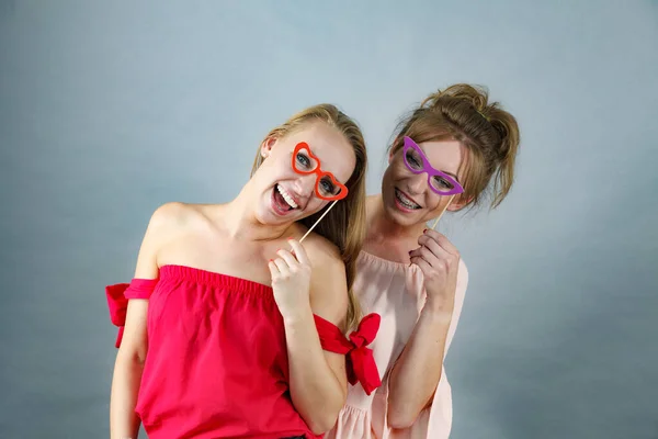 眼鏡をかけるふりをする楽しさを持つ棒にシンボルを持つ2人の幸せな女性 写真とカーニバル面白いアクセサリーコンセプト — ストック写真