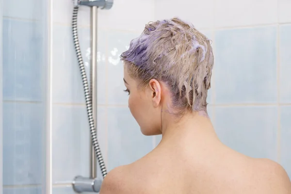 シャワーの下に紫色のシャンプーフォームを頭の上に持っている女性 カラーシャンプーを使用した女性のトーニングブロンドの髪 — ストック写真