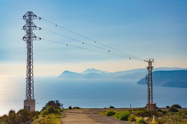 Elektrik iletim direkleriyle kıyı şeridi, elektrik hatları yüksek voltaj kuleleri. İspanya 'da kıyı manzarası