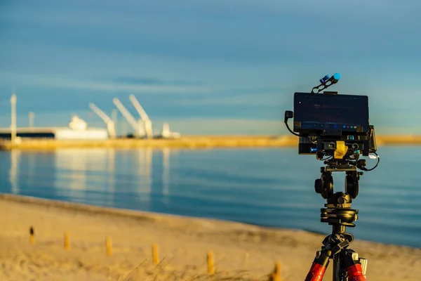 Camera on tripod take photo from industry landscape, sea port. View from beach near Gandia, Valencia Spain