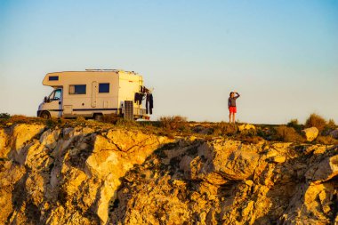 Karavanla seyahat eden bir kadın. Kamp aracı, Endülüs İspanya 'nın Almerya eyaletindeki Cabo de Gata Nijar Doğal Parkı' nda kayalıklarda kamp yapıyor..