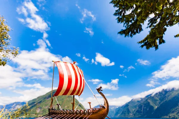 Old wooden viking longboat sails, drakkar boat on fjord shore in Norway. Tourism and traveling concept