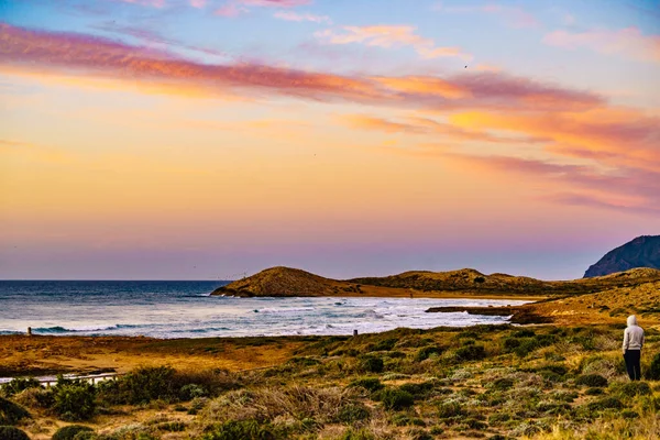Person on beach looking at sea, enjoying morning coastal landscape. Calblanque Regional Park, Murcia region in Spain.