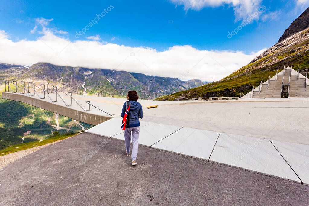 Woman with norwegian flag on Utsikten viewpoint at Gaularfjellet. Tourist attraction. Scenic route in Norway.