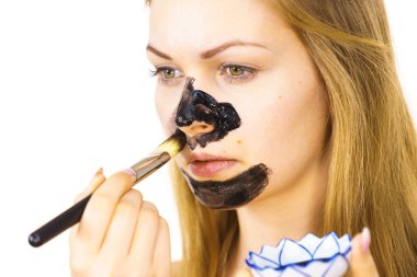 Genç bir kadın yüzüne siyah kozmetik sürerek kömür maskesini temizliyor. Yağlı ciltle ilgilenen bir kadın. Güzellik tedavisi. Cilt bakımı.