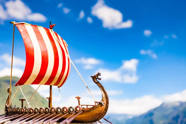 Old wooden viking longboat sails, drakkar boat on fjord shore in Norway. Tourism and traveling concept