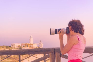Kameralı kadın turist Mesa Roldán deniz fenerinden fotoğraf çekiyor. Cabo de Gata Nijar Doğal Parkı, Endülüs İspanya.