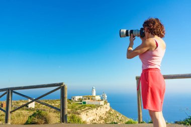 Kameralı kadın turist Mesa Roldán deniz fenerinden fotoğraf çekiyor. Cabo de Gata Nijar Doğal Parkı, Endülüs İspanya.