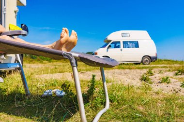 Güverte sandalyesinde kadın ayakları. Güneşli yaz gününde karavanın önünde güneşlenen kadın dinleniyor...