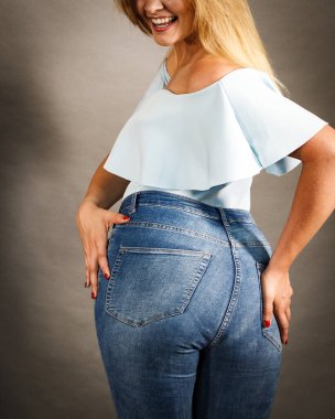 Kadın artı beden kalçalı, kot pantolon giyen, şık giyinen bir kadın. Moda kıyafetleri kadınlık konsepti. Gri arkaplan