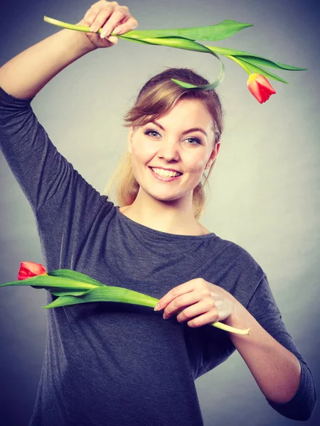 美容自然植物カジュアルファッションコンセプト 2本のチューリップを持つブロンドの女性 若いです笑顔の女の子維持赤い花で手 — ストック写真