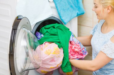 Banyodaki kadın çamaşırları düzenliyor, çamaşır makinesini renklendiriyor. Ev işleri..