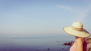 Yazlık şapkalı olgun bir kadın İspanya 'nın sahil manzarasının tadını çıkarıyor. Yaz tatili.