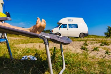 Güverte sandalyesinde kadın ayakları. Güneşli yaz gününde karavanın önünde güneşlenen kadın dinleniyor...