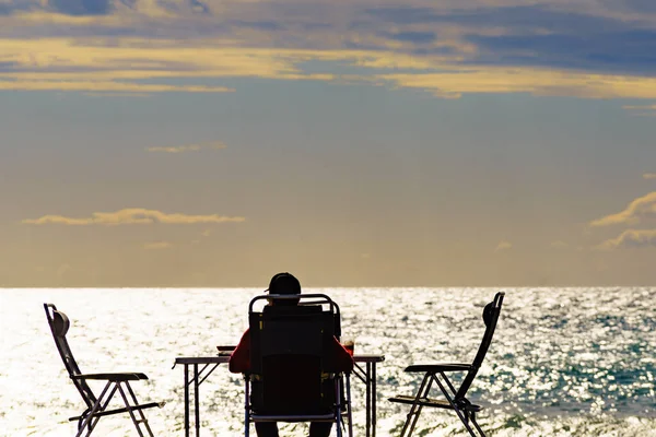 日落时分 男性游客坐在海滩上 悠闲地欣赏风景 — 图库照片