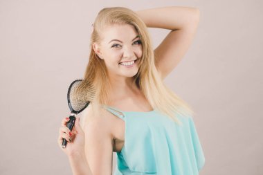 Güzel, uzun, açık sarı saçlarını tarayan neşeli sarışın kadın saç bakımının sonuçlarını görüyor..