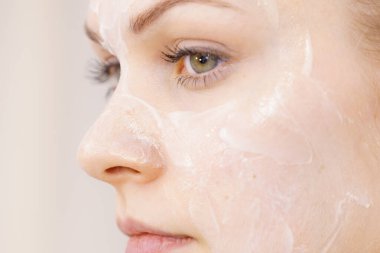 Yüzünde krem kozmetik, maske ve nem olan genç bir kadın. Güzellik tedavisi. Cilt bakımı.