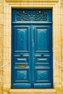 Eski ahşap mavi giriş kapısı olan taş ev cephesi. Fransa 'da mimarlık.