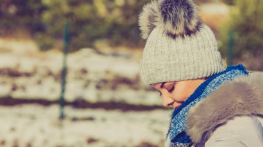Kış boyunca sıcak aksesuarlar takan güzel bir genç kadın. Gri bereli, ponpon şapkalı ve mavi atkılı bir kadın..