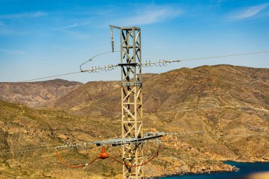 İspanyol dağlık kayalık kıyı şeridi elektrik iletim pilonu, elektrik hattı voltaj kulesi.