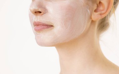 Yüzünde krem kozmetik, maske ve nem olan genç bir kadın. Güzellik tedavisi. Cilt bakımı.