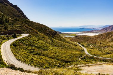İspanyol dağları manzarası ve vadide birçok serası olan deniz kıyısı manzarası. Castillitos Bataryası 'na giden dolambaçlı yol.