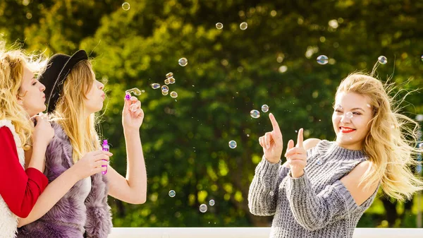 一群年轻的时尚女性好友一边在户外享受阳光灿烂的日子 一边用玩具泡泡棒一起吹泡泡 幸福和无忧无虑的概念 — 图库照片