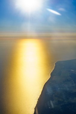 Gün doğumunda bir uçak penceresinden Baltık Denizi kıyısına bakın. Polonya üzerinde uçan uçaklar Avrupa.