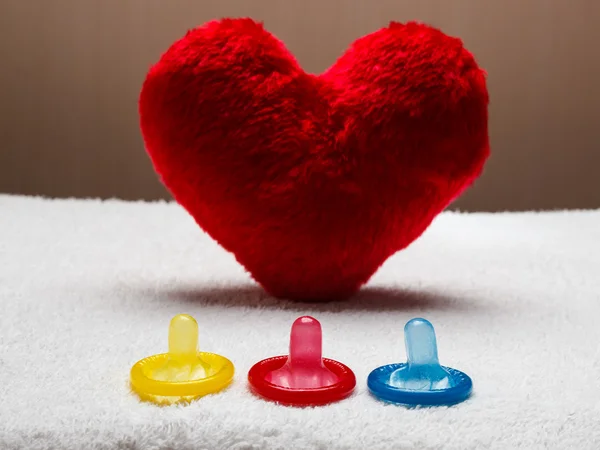 Барвисті презервативи і червоне серце — стокове фото
