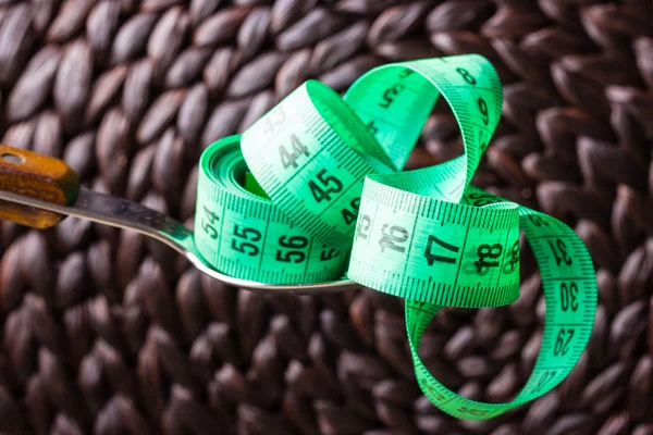 Green measuring tape on kitchen spoon — Stock Photo, Image