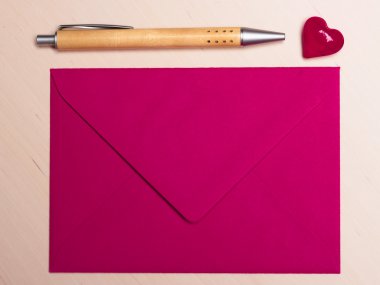 Pink envelope heart and pen on table